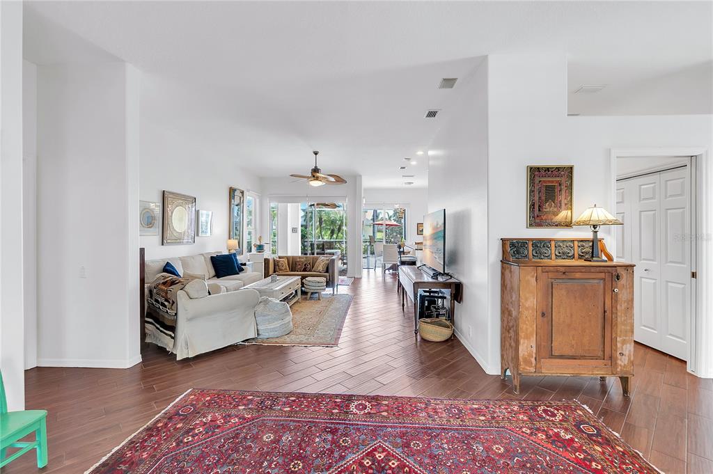 A living room with wood-look tile floors, a large area rug, and a television console — 4616 BLUE MARLIN DRIVE, BRADENTON, FL