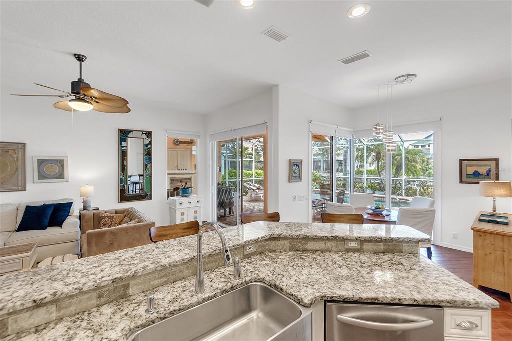 A kitchen island with granite countertops overlooks a living area and a dining room — 4616 BLUE MARLIN DRIVE, BRADENTON, FL
