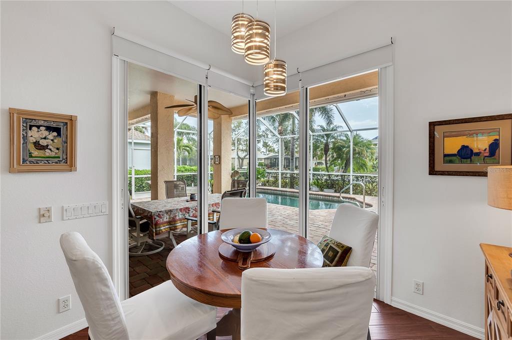A dining area with a round table and chairs overlooks a screened-in pool patio — 4616 BLUE MARLIN DRIVE, BRADENTON, FL