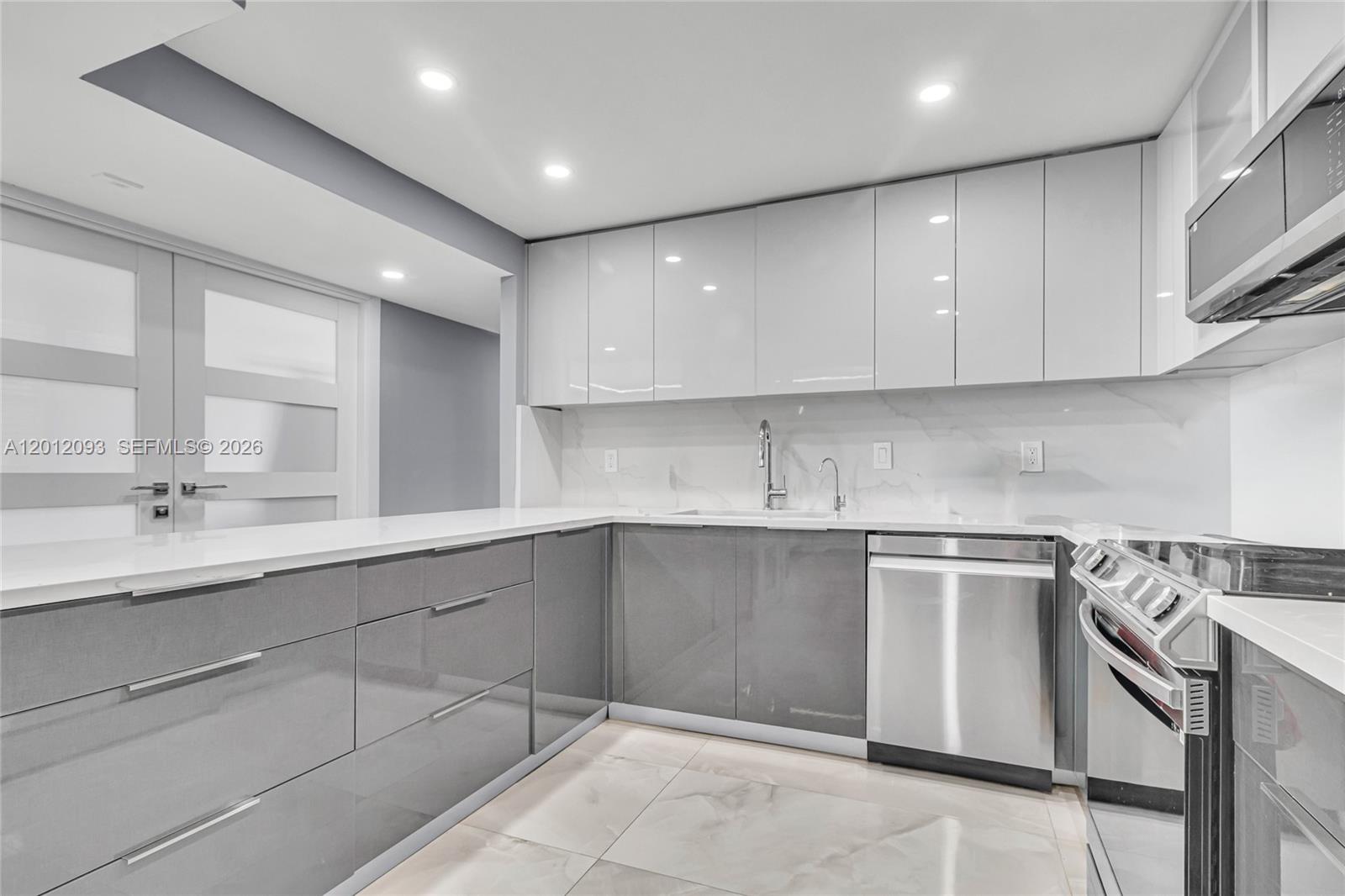 A modern kitchen features gray lower cabinets, white upper cabinets, and white marble-style countertops — 3161 S Ocean Dr # 1107, Hallandale Beach FL 33009, HALLANDALE BEACH, FL
