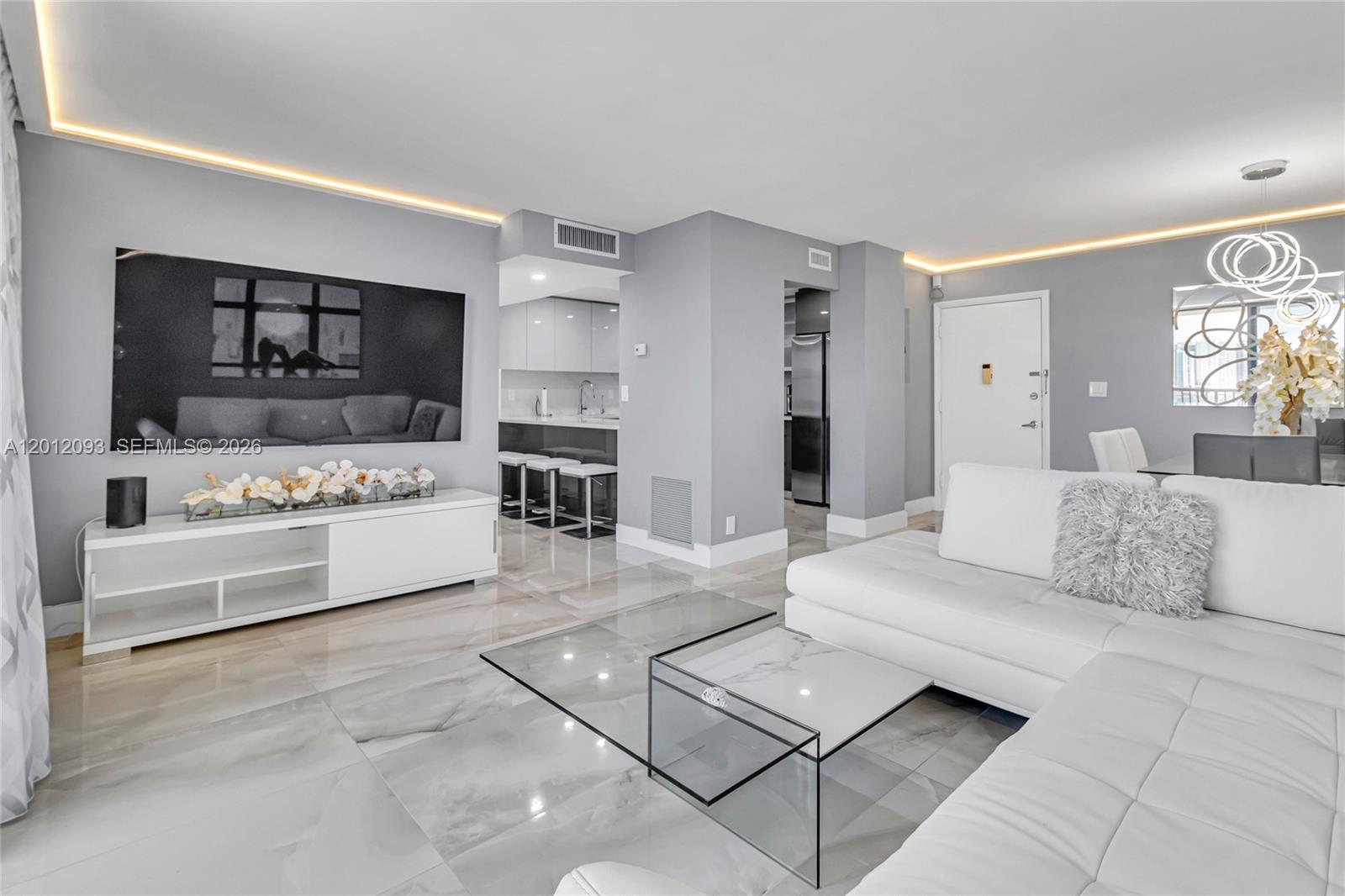 A modern living room features white furniture, a glass coffee table, and glossy marble flooring — 3161 S Ocean Dr # 1107, Hallandale Beach FL 33009, HALLANDALE BEACH, FL