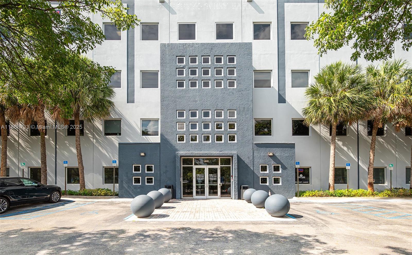 The exterior of a multi-story commercial building features a gray facade with a grid of windows — 7791 NW 46th St # 428, Doral FL 33166, DORAL, FL