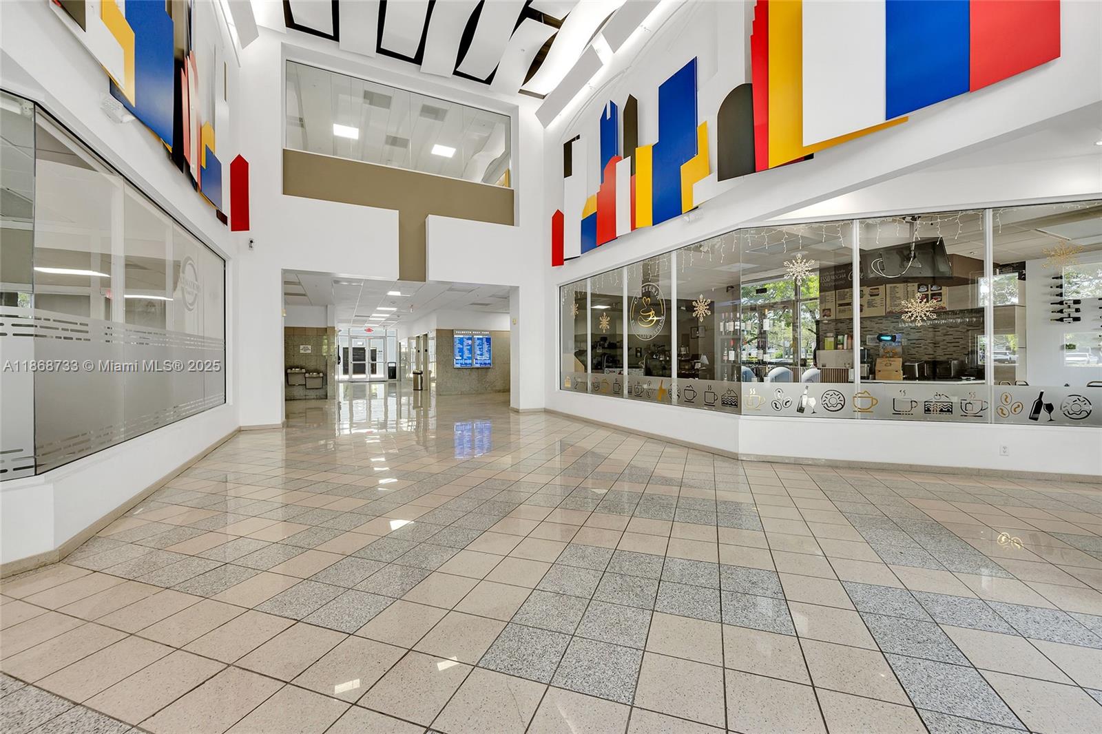 A bright, tiled lobby features glass-walled storefronts and colorful geometric wall art — 7791 NW 46th St # 428, Doral FL 33166, DORAL, FL