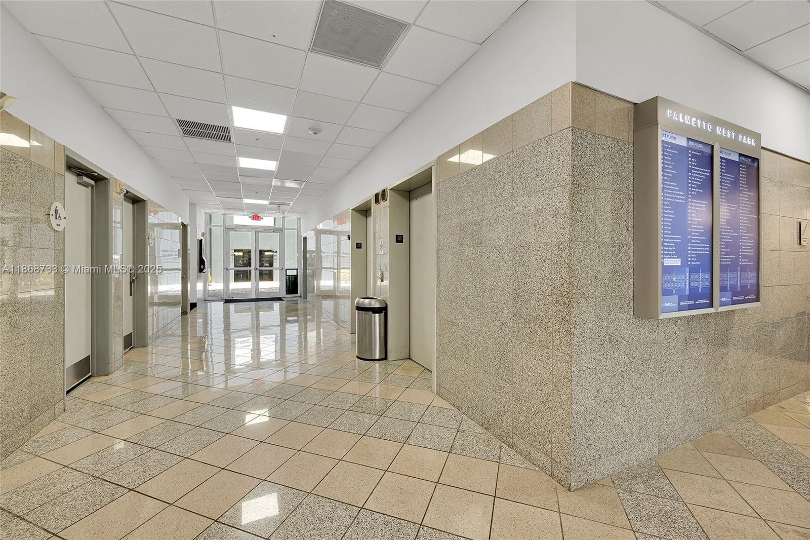 A commercial building hallway features tiled floors, elevator doors, and a wall-mounted directory sign — 7791 NW 46th St # 428, Doral FL 33166, DORAL, FL