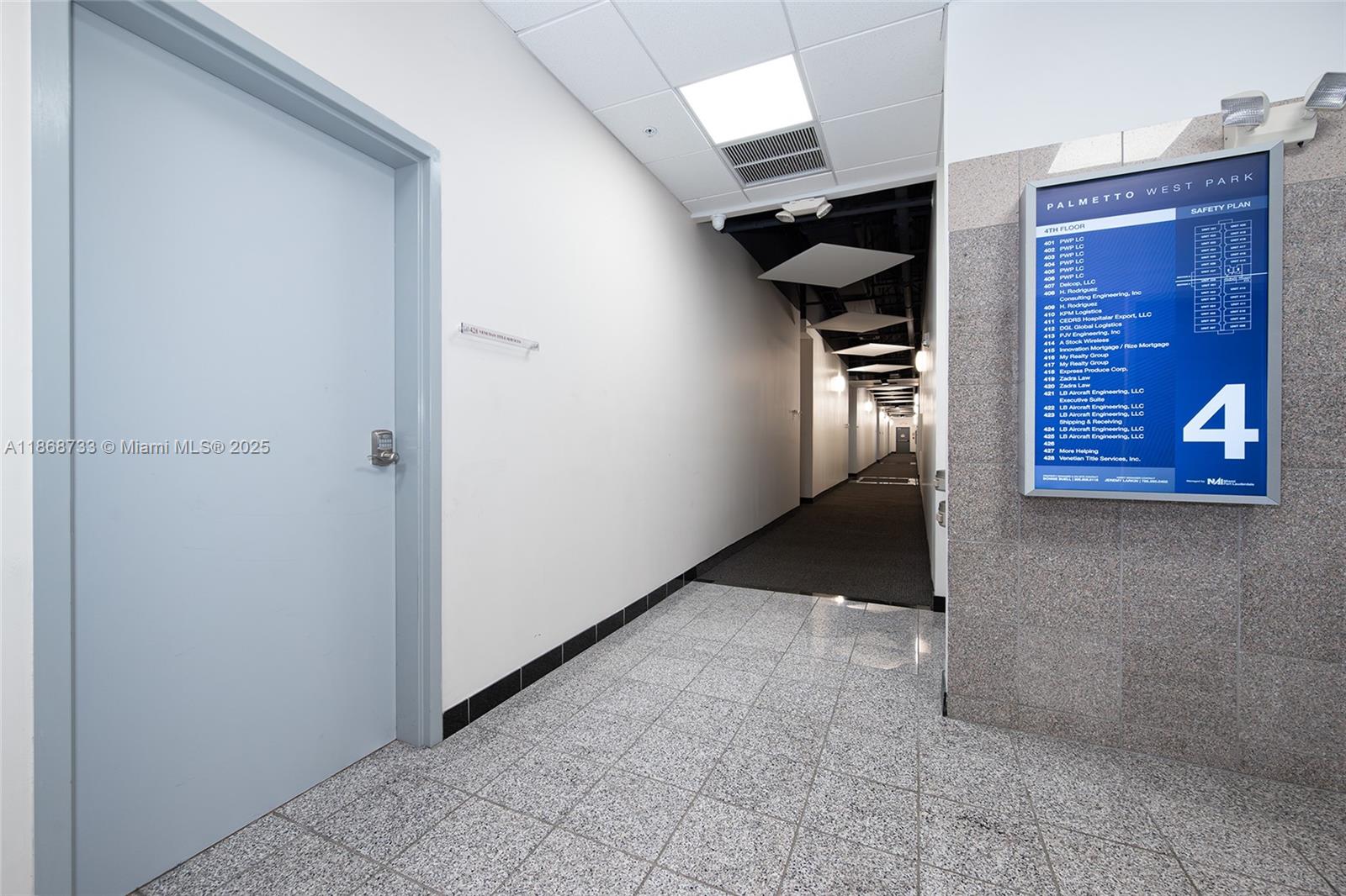 A hallway features a grey door, tiled flooring, and a directory sign on a stone wall — 7791 NW 46th St # 428, Doral FL 33166, DORAL, FL