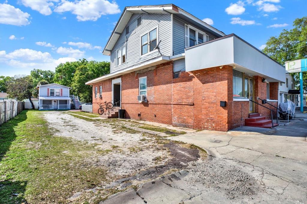 A two-story building with a brick lower level and gray siding above sits beside a driveway — 5210 N NEBRASKA AVENUE, TAMPA, FL