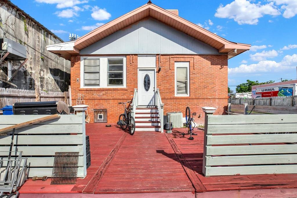 A red brick house features a large wooden deck and a front entrance with stairs — 5210 N NEBRASKA AVENUE, TAMPA, FL