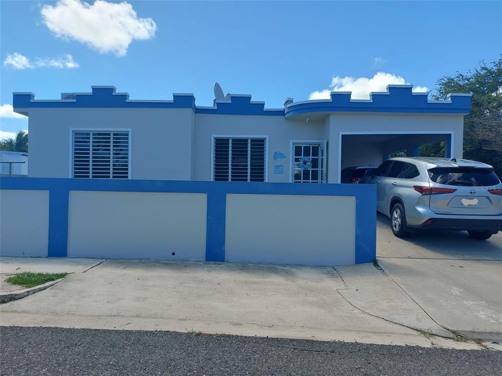 A single-story house with a flat roof, blue trim, and a concrete perimeter wall — Carr. 459 BARRIO CEIBA ALTA, AGUADILLA, PR