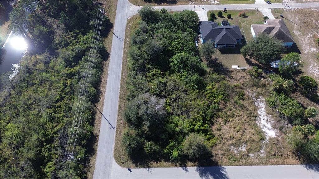An aerial view shows a vacant, wooded residential lot situated between two paved roads — 880 GULF LANE, LEHIGH ACRES, FL