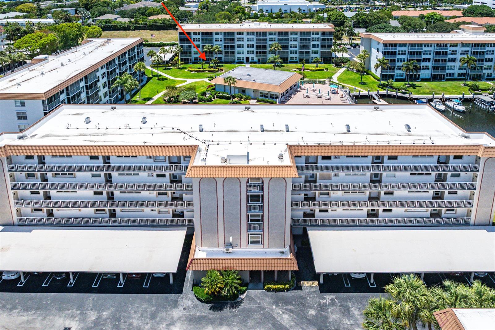 An aerial view shows multiple multi-story apartment buildings with parking structures and a central pool — 2717 Florida Boulevard # 125, Delray Beach FL 33483, DELRAY BEACH, FL
