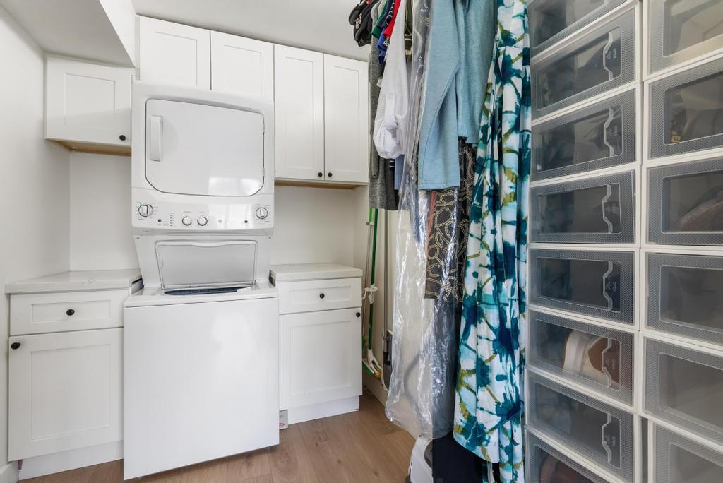 A laundry room features white cabinetry, a stacked washer and dryer, and a shoe storage unit — 2717 Florida Boulevard # 125, Delray Beach FL 33483, DELRAY BEACH, FL