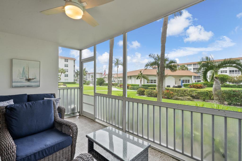 A screened-in patio features wicker furniture, a ceiling fan, and views of a landscaped courtyard — 2717 Florida Boulevard # 125, Delray Beach FL 33483, DELRAY BEACH, FL