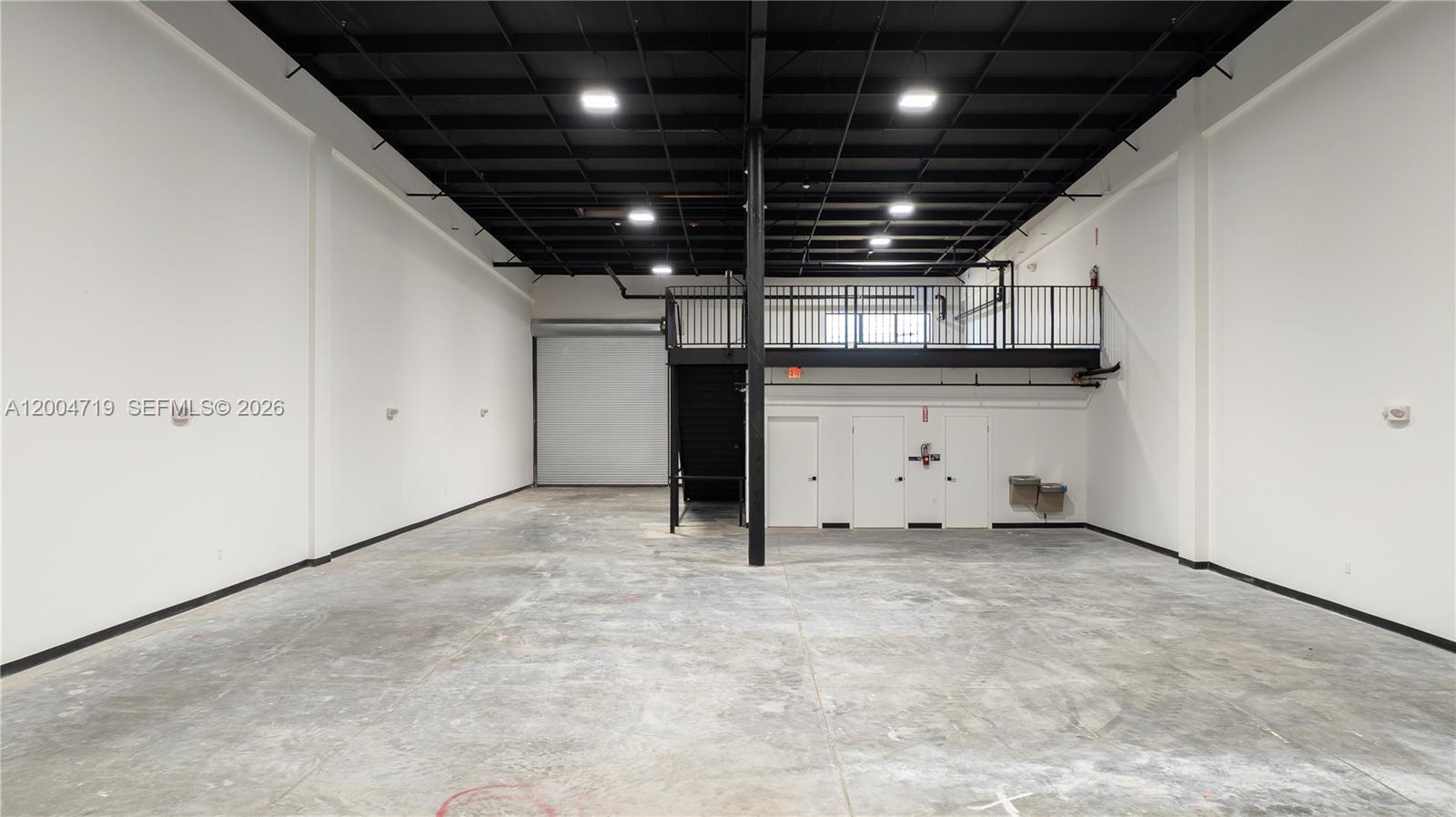 An industrial warehouse space features a concrete floor, white walls, and an elevated mezzanine level — 7265 NW 74th St # 6, Medley FL 33166, MEDLEY, FL