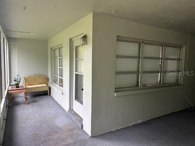 A covered porch features gray carpeting, a small wooden table, a bench, and windows — 2030 HEALY DRIVE, CLEARWATER, FL
