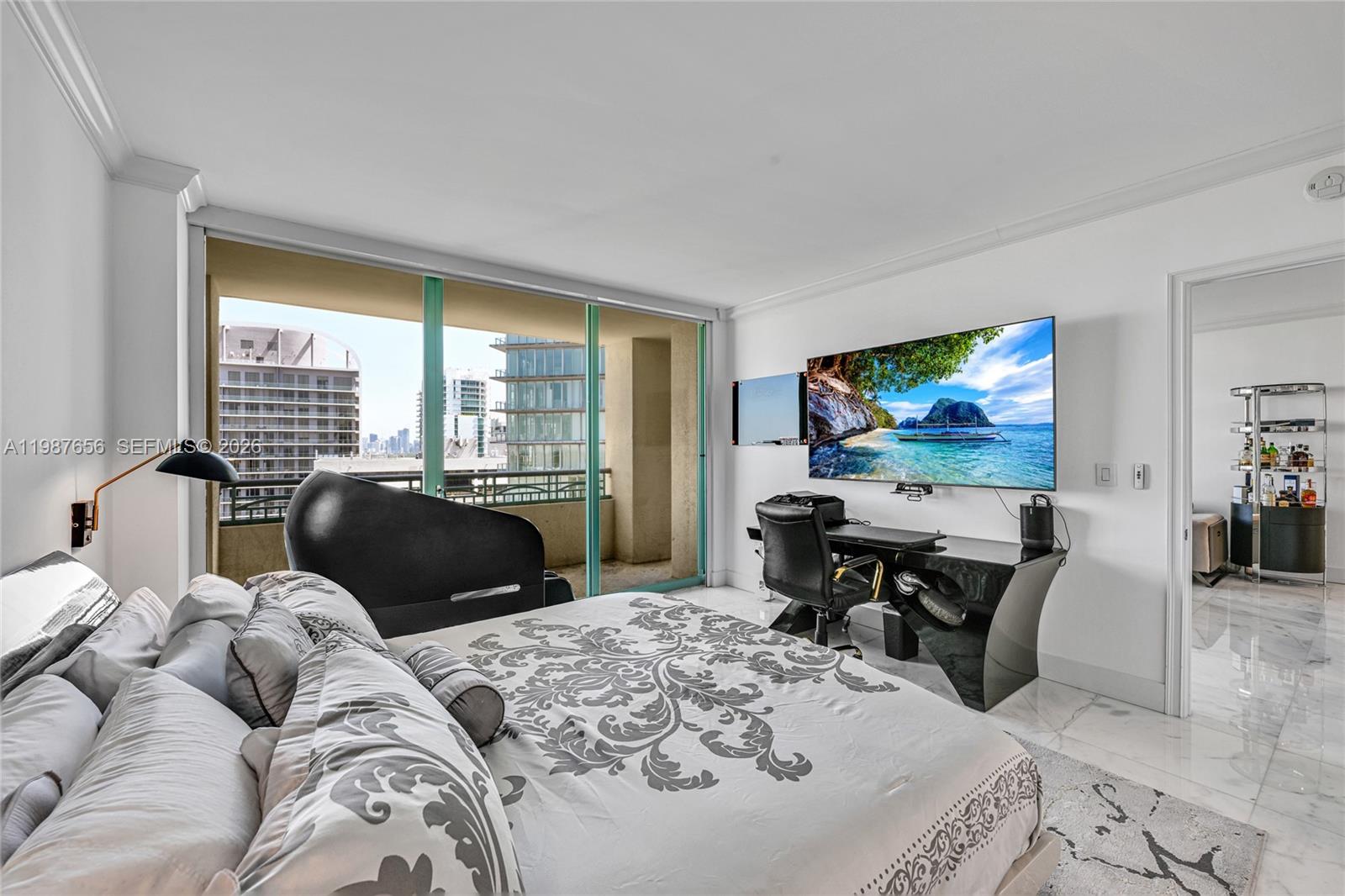 A bedroom features a bed, a desk with a television, and a balcony with city views — 3350 SW 27th Ave # 1908, Coconut Grove FL 33133, COCONUT GROVE, FL