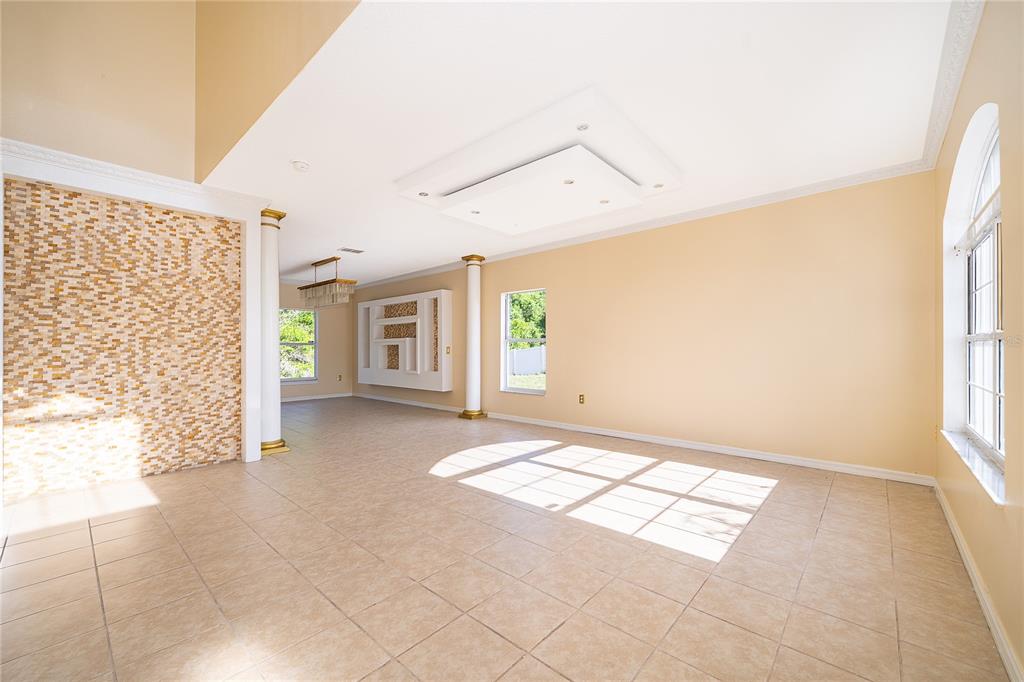 A spacious living area features tile floors, a mosaic accent wall, and a tray ceiling — 1204 APOPKA DRIVE, POINCIANA, FL