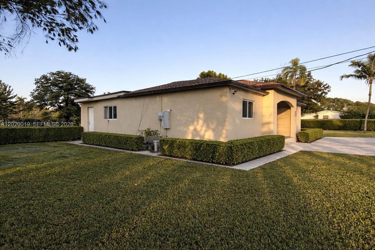 A single-story beige house with a flat roof and manicured hedges sits on a lawn — 2295 NW 115th St, Miami FL 33167, MIAMI, FL