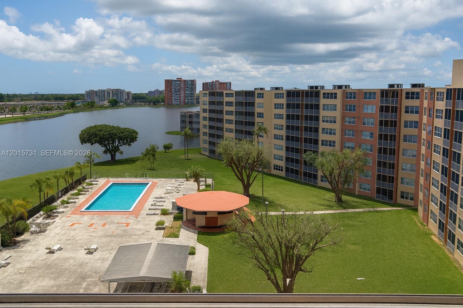 An elevated view shows a swimming pool, a gazebo, and a large apartment building near a lake — 1750 NE 191st St # 3, Miami FL 33179, MIAMI, FL