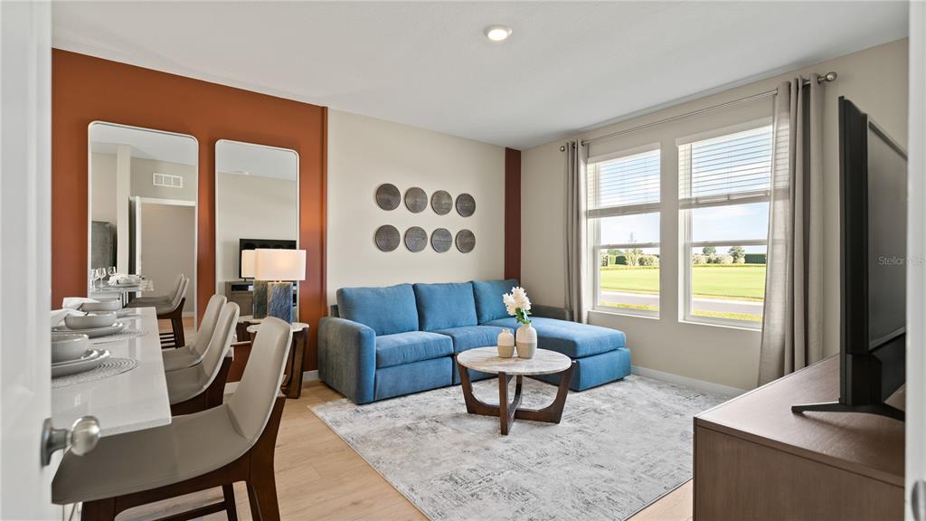 A living room features a blue sectional sofa, a coffee table, and an accent wall — 4886 WALTHAM FOREST DRIVE, DAVENPORT, FL