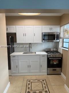 A kitchen features white cabinets, stainless steel appliances, a sink, and light-colored tile flooring — 321 Wilson St # A204, Hollywood FL 33019, HOLLYWOOD, FL
