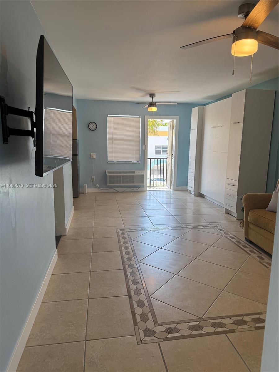 A living area features light blue walls, tile flooring with a decorative border, and a balcony — 321 Wilson St # A204, Hollywood FL 33019, HOLLYWOOD, FL