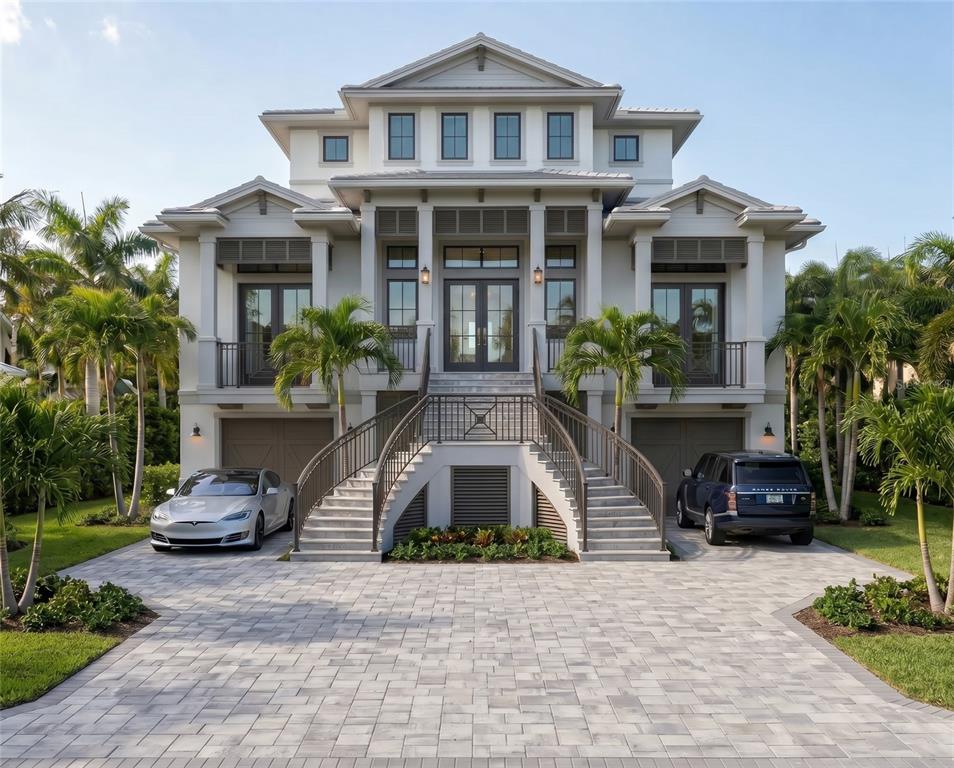 A three-story house with a symmetrical exterior, dual staircases, and a paved driveway with cars — 4223 HAWK ISLAND DRIVE, BRADENTON, FL