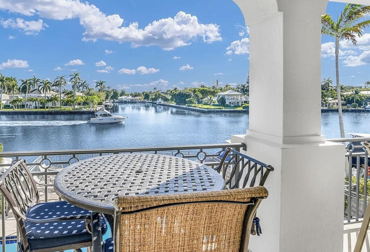 A balcony with outdoor furniture overlooks a canal with a boat and waterfront homes — 3042 WATERSIDE Circle, Boynton Beach FL 33435, BOYNTON BEACH, FL