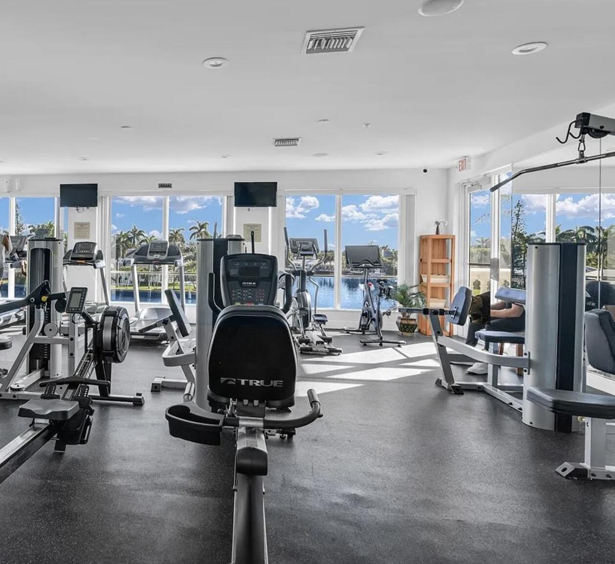 A gym with various exercise machines, black flooring, and large windows overlooking a waterfront view — 3042 WATERSIDE Circle, Boynton Beach FL 33435, BOYNTON BEACH, FL