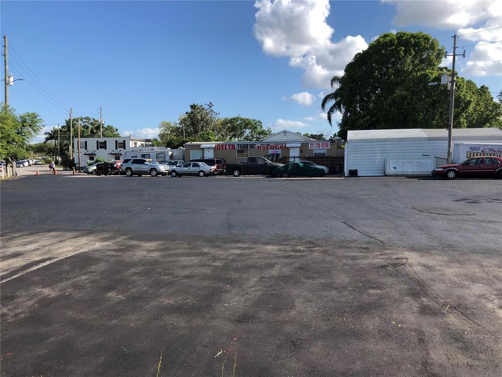 A paved parking lot fronts a commercial building with a used car dealership sign — 6180 HAINES ROAD N, ST PETERSBURG, FL