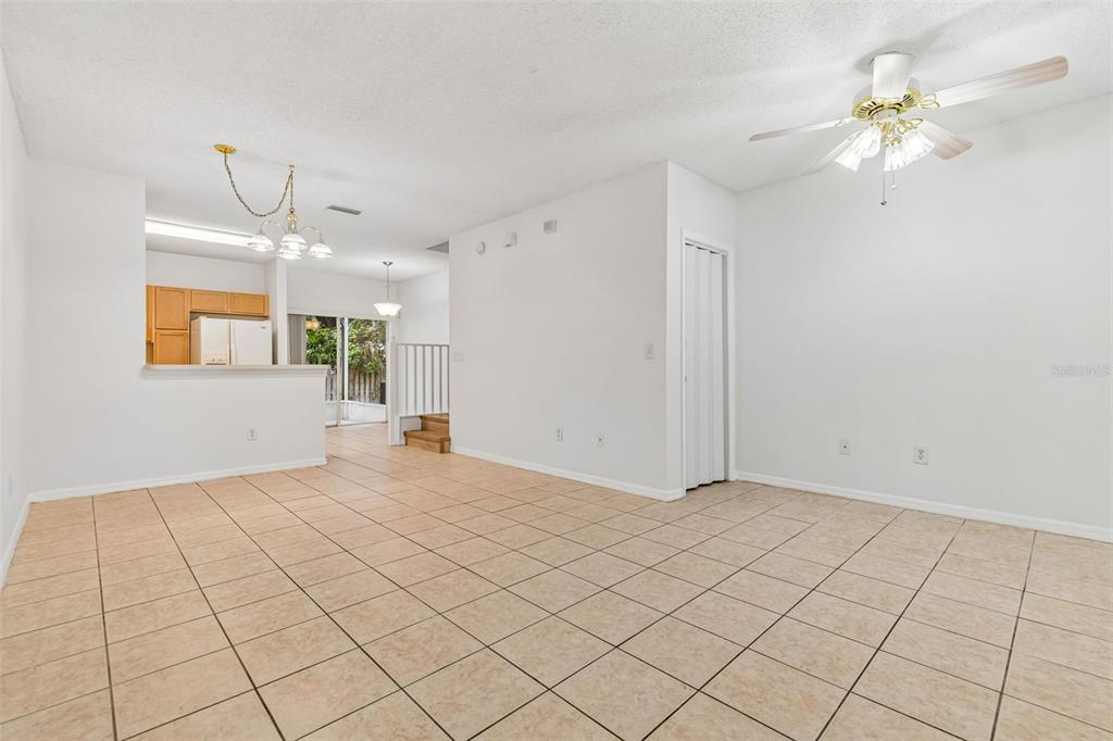 A bright, tiled living area features a ceiling fan, a kitchen pass-through, and stairs — 6245 OSPREY LAKE CIRCLE, RIVERVIEW, FL