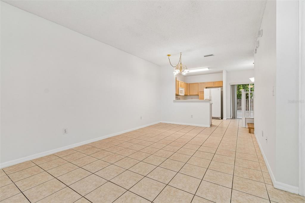An open-concept living and dining area features beige tile flooring and a kitchen pass-through window — 6245 OSPREY LAKE CIRCLE, RIVERVIEW, FL