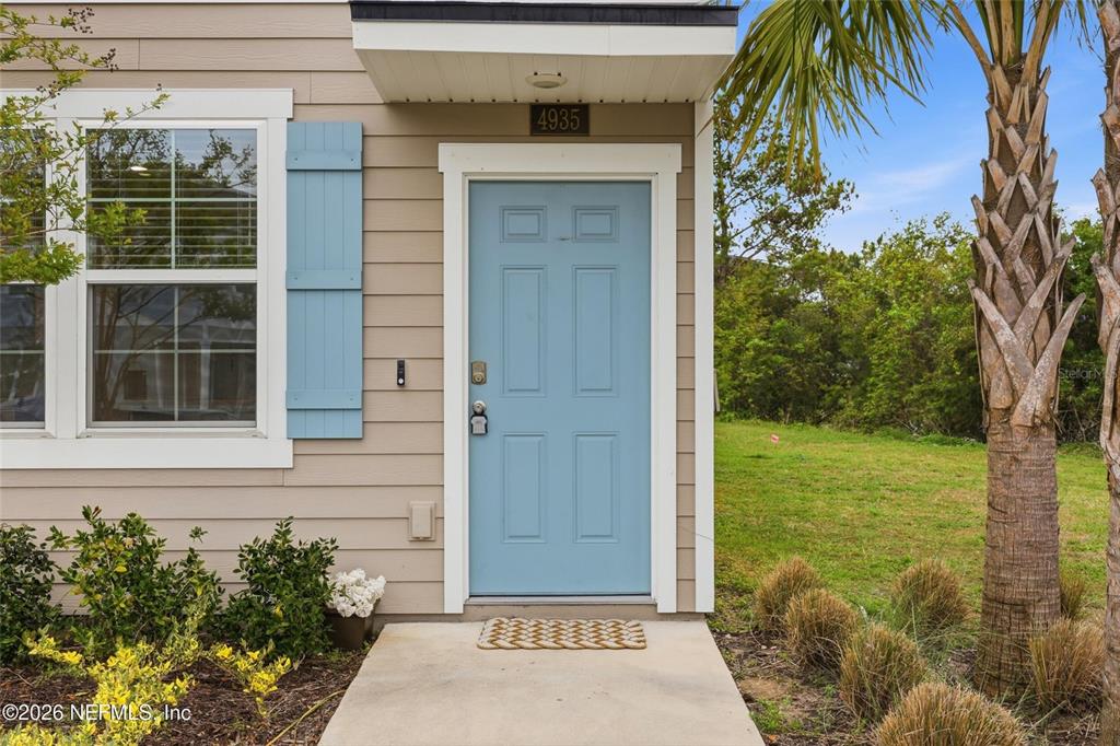 The exterior of a house features a light blue front door and tan siding — 4935 NEBULA LANE, JACKSONVILLE, FL