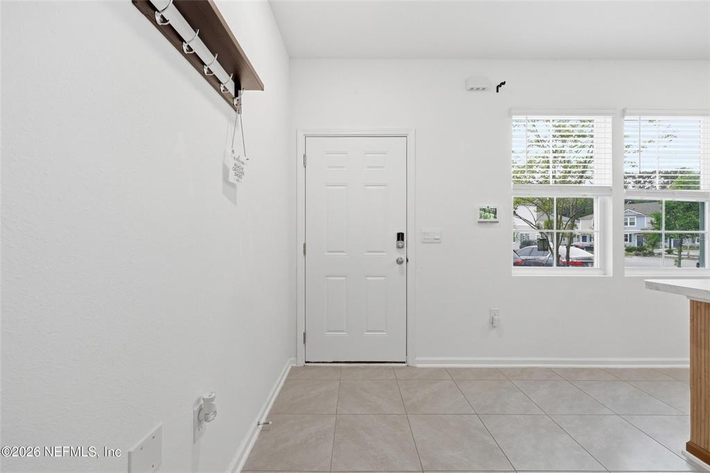 This entryway features a white door, tile flooring, and a wall-mounted coat rack — 4935 NEBULA LANE, JACKSONVILLE, FL