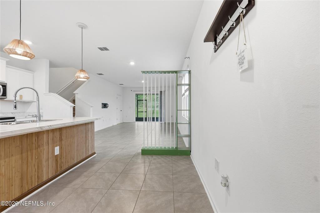 A kitchen island with a wood-paneled base faces an open living area with tile flooring — 4935 NEBULA LANE, JACKSONVILLE, FL