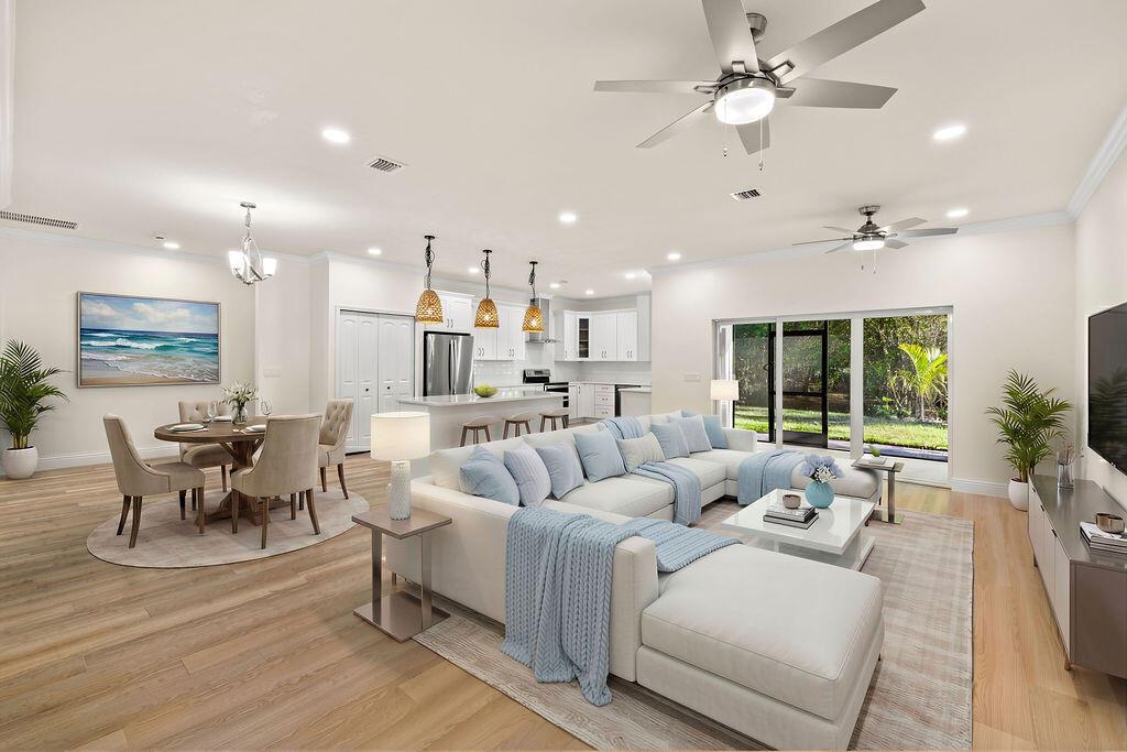 An open-concept living and dining area features light wood floors, a sectional sofa, and kitchen — 4805 66th Lane, Vero Beach FL 32967, VERO BEACH, FL