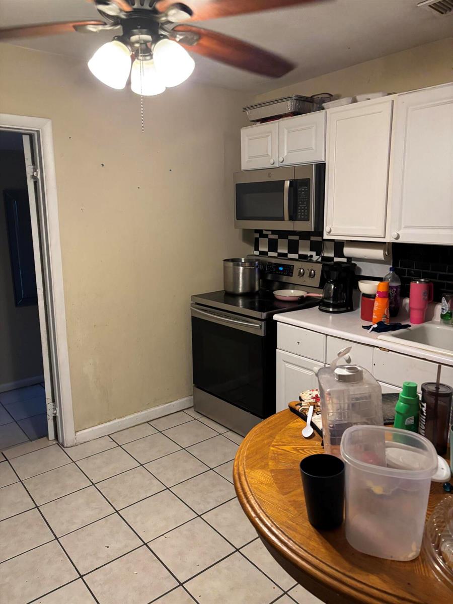 A kitchen features white cabinets, a stainless steel microwave, a stove, and tiled flooring — 390 SW 7th Rd Road SW, Vero Beach FL 32962, VERO BEACH, FL