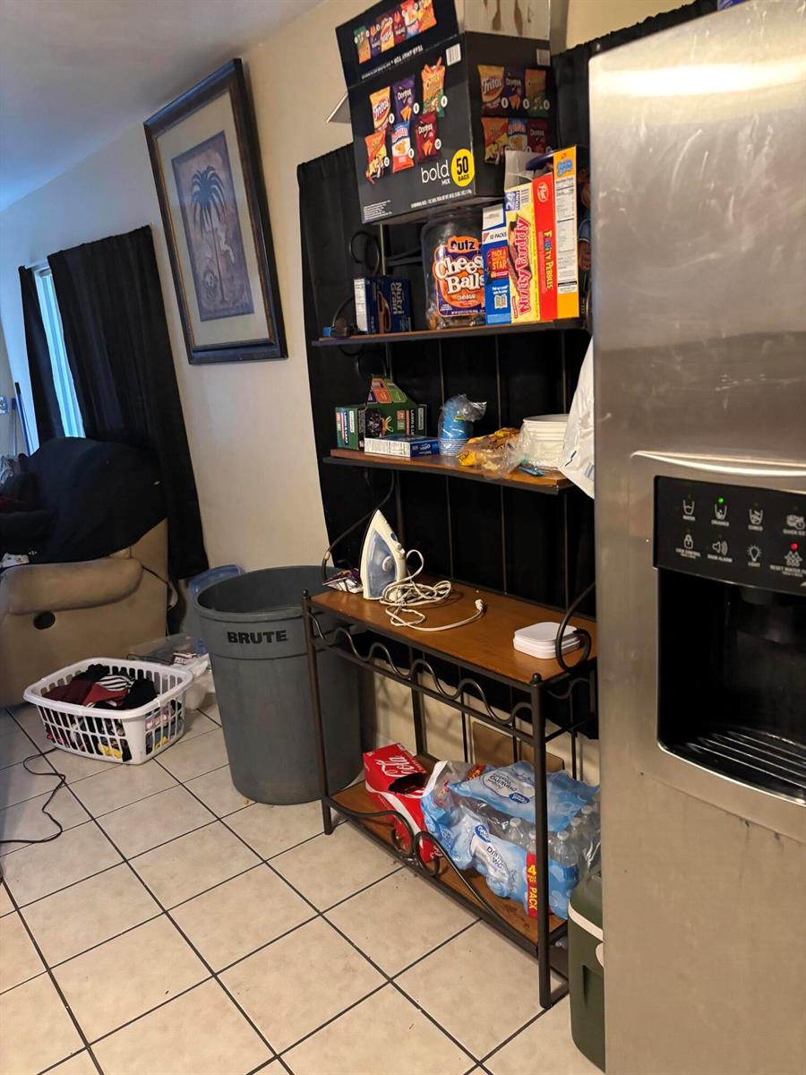 A kitchen area features a metal shelving unit, a large trash can, and a refrigerator — 390 SW 7th Rd Road SW, Vero Beach FL 32962, VERO BEACH, FL