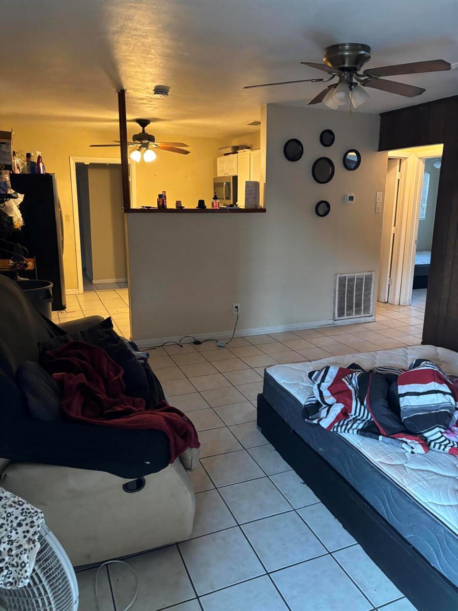 A living room with tile flooring, a ceiling fan, and an open view into the kitchen — 390 SW 7th Rd Road SW, Vero Beach FL 32962, VERO BEACH, FL