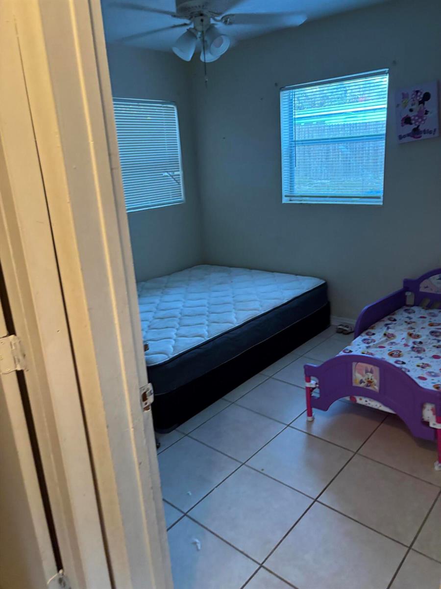 A bedroom features a mattress on a box spring, a toddler bed, and tiled flooring — 390 SW 7th Rd Road SW, Vero Beach FL 32962, VERO BEACH, FL