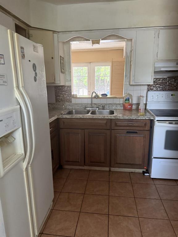 A kitchen features wood cabinets, a double sink, a white refrigerator, and tile flooring — 2509 25TH AVENUE W, BRADENTON, FL