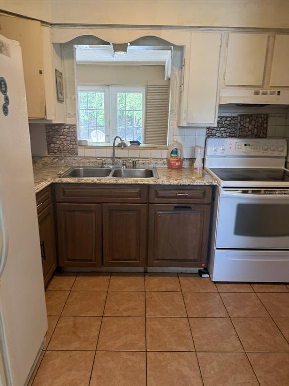 A kitchen features brown lower cabinets, white upper cabinets, a double sink, and tile flooring — 2509 25TH AVENUE W, BRADENTON, FL