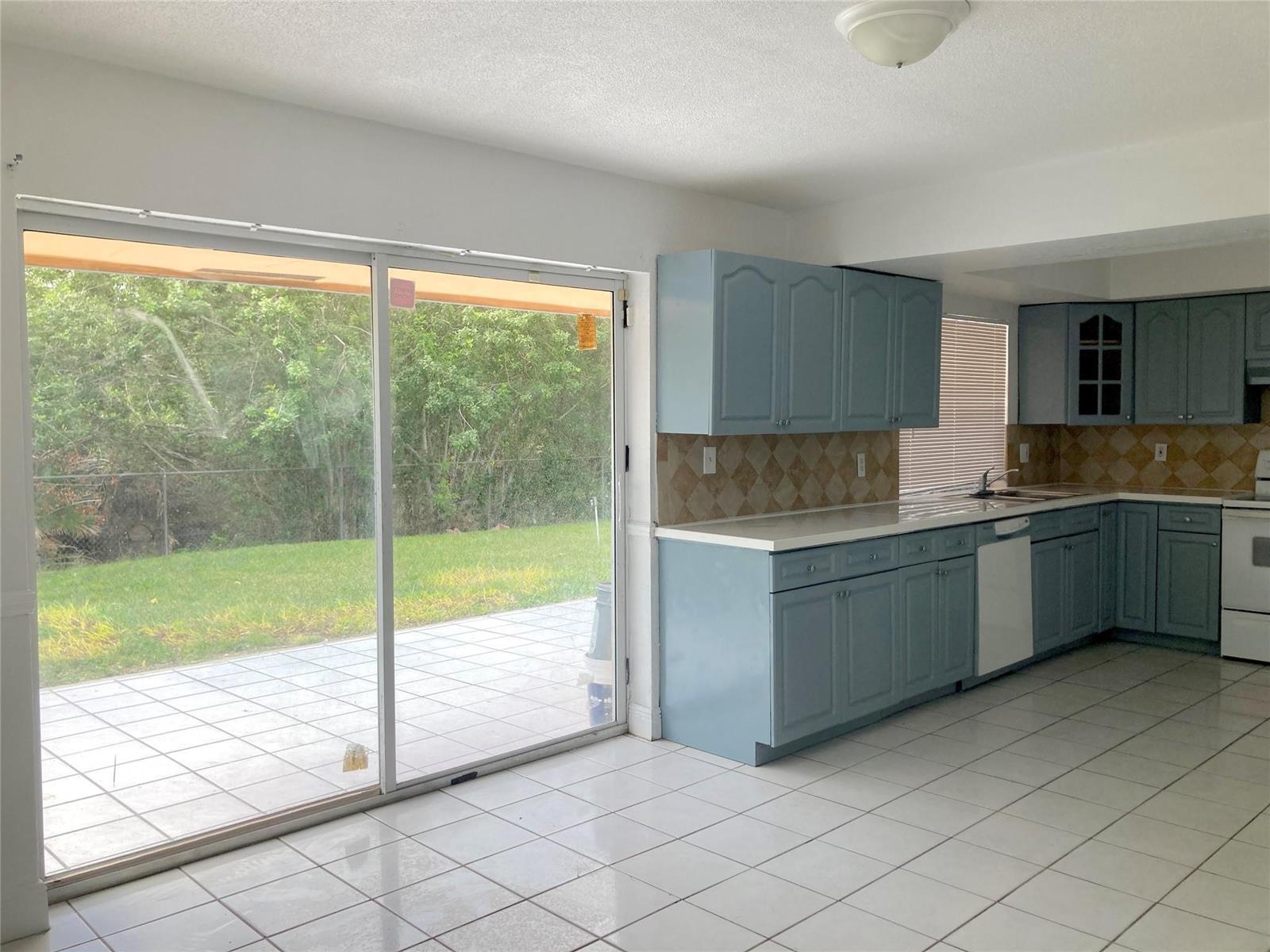 A kitchen with blue cabinets, tile flooring, and a sliding glass door to a patio — 6230 SW 4th Place, Margate FL 33068, MARGATE, FL