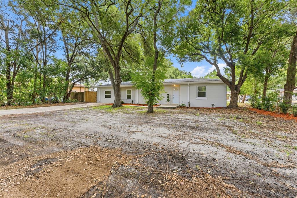 A single-story house with a concrete driveway and large trees in the front yard — 264 14TH STREET NW, LARGO, FL
