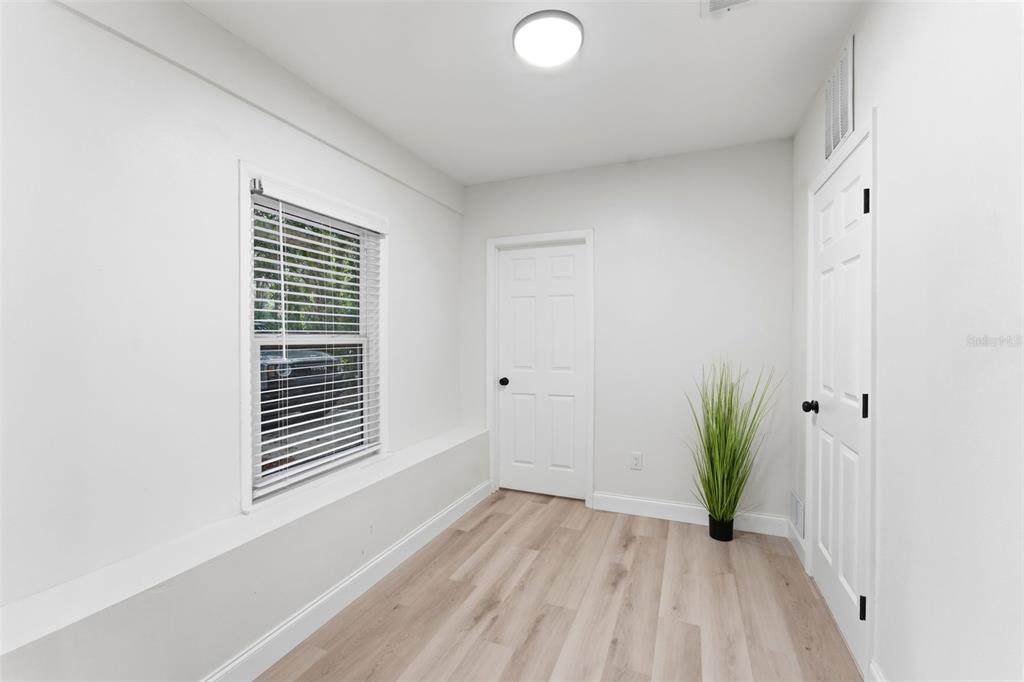 A bright, open-concept living area features light wood-look flooring and a kitchen with white cabinetry — 264 14TH STREET NW, LARGO, FL