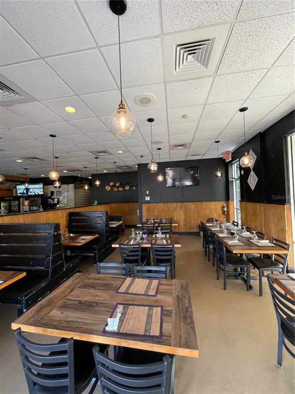 A restaurant dining room features wooden tables, black chairs, and dark wainscoting under a drop ceiling — 5907 ROOSEVELT BOULEVARD, JACKSONVILLE, FL