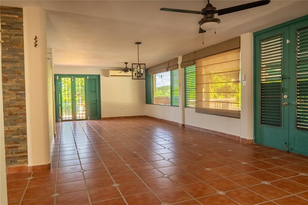 An open-concept room features terracotta tile floors, a ceiling fan, and green-framed glass doors — #12 CALLE CENTRAL HACIENDA MARGARITA, LUQUILLO, PR