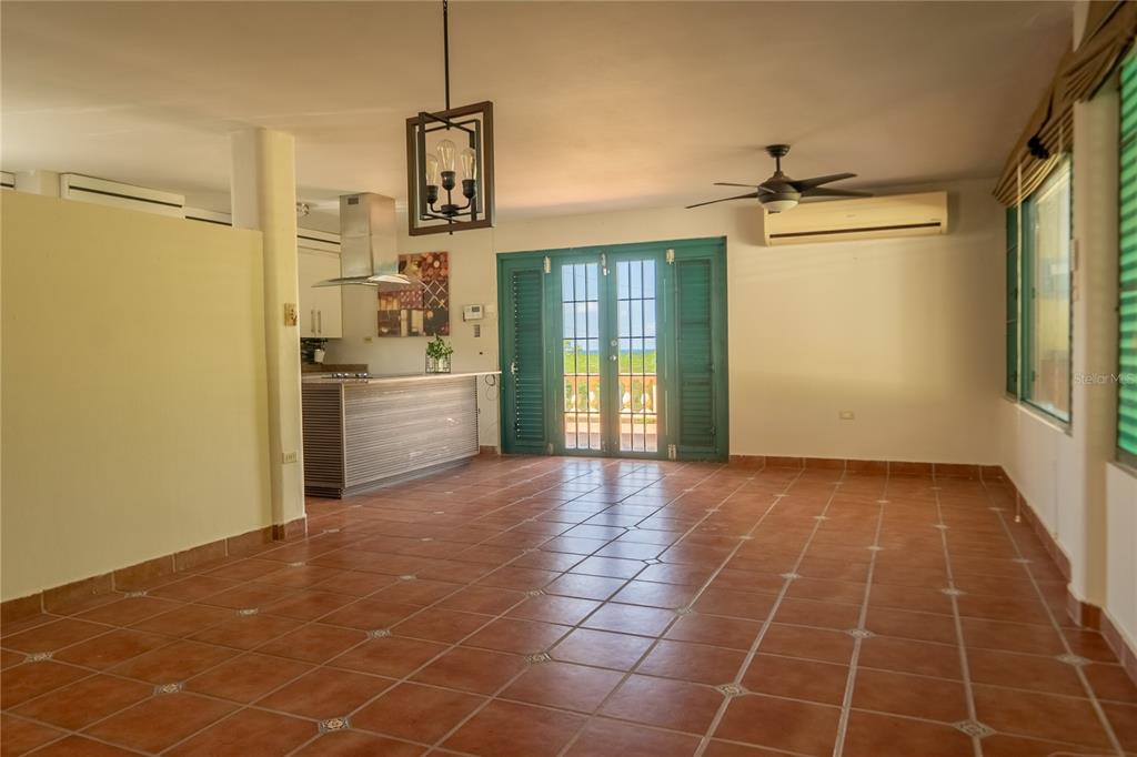 An open-concept living and kitchen area features terracotta tile floors and green louvered doors — #12 CALLE CENTRAL HACIENDA MARGARITA, LUQUILLO, PR