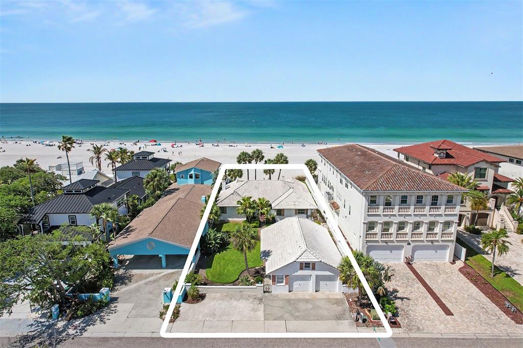 An aerial view shows a beachfront property with a house, detached garage, and lawn — 18206 SUNSET BOULEVARD, REDINGTON SHORES, FL