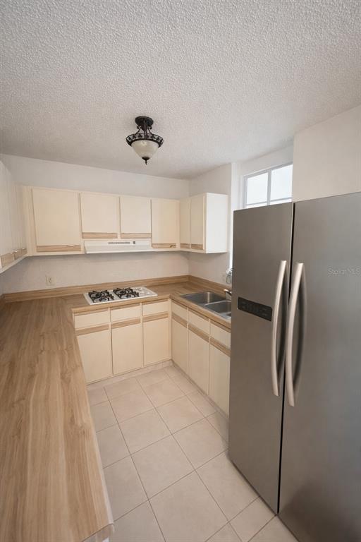 A kitchen features light-colored cabinets, wood-look countertops, a stainless steel refrigerator, and tiled flooring — C3120 CIPRES, TOA BAJA, PR