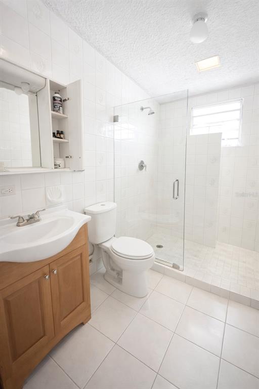 A bathroom features a wooden vanity, a white toilet, and a glass-enclosed walk-in shower — C3120 CIPRES, TOA BAJA, PR